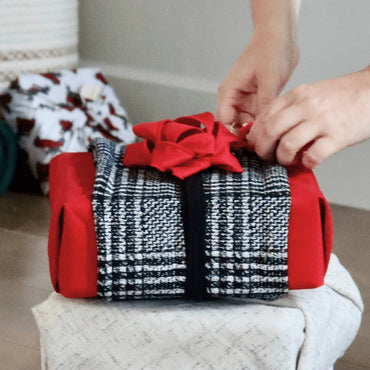 Reusable gift wrapping Vice-Versaᴷᴵᵀ - Black, silver, and white checkered band on a red Furoshiki and a red gift bow