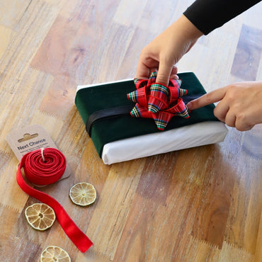 Reusable gift wrapping Vice-Versaᴷᴵᵀ - Forest green corduroy band on a white Furoshiki and a red and green tartan gift bow
