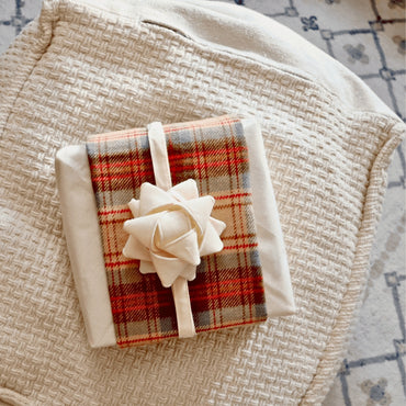 Reusable gift wrapping Vice-Versaᴷᴵᵀ - Red, beige, and gray tartan wool band on a cream Furoshiki and a cream gift bow