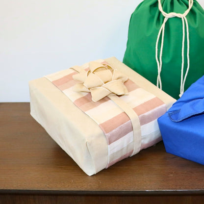 Reusable gift wrapping Vice-Versaᴷᴵᵀ - Multicolored striped band on a light blue Furoshiki and a white bow